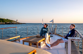 Guests on the bow of yacht Full Moon in Newport RI with a lighthouse in the background