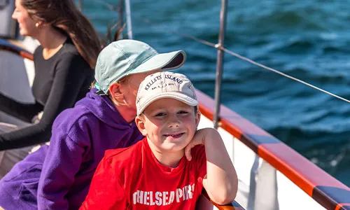 Newport_Ticket-Cruises_Our-Reviews closeup of a kid smiling, aboard a sailboat on the water